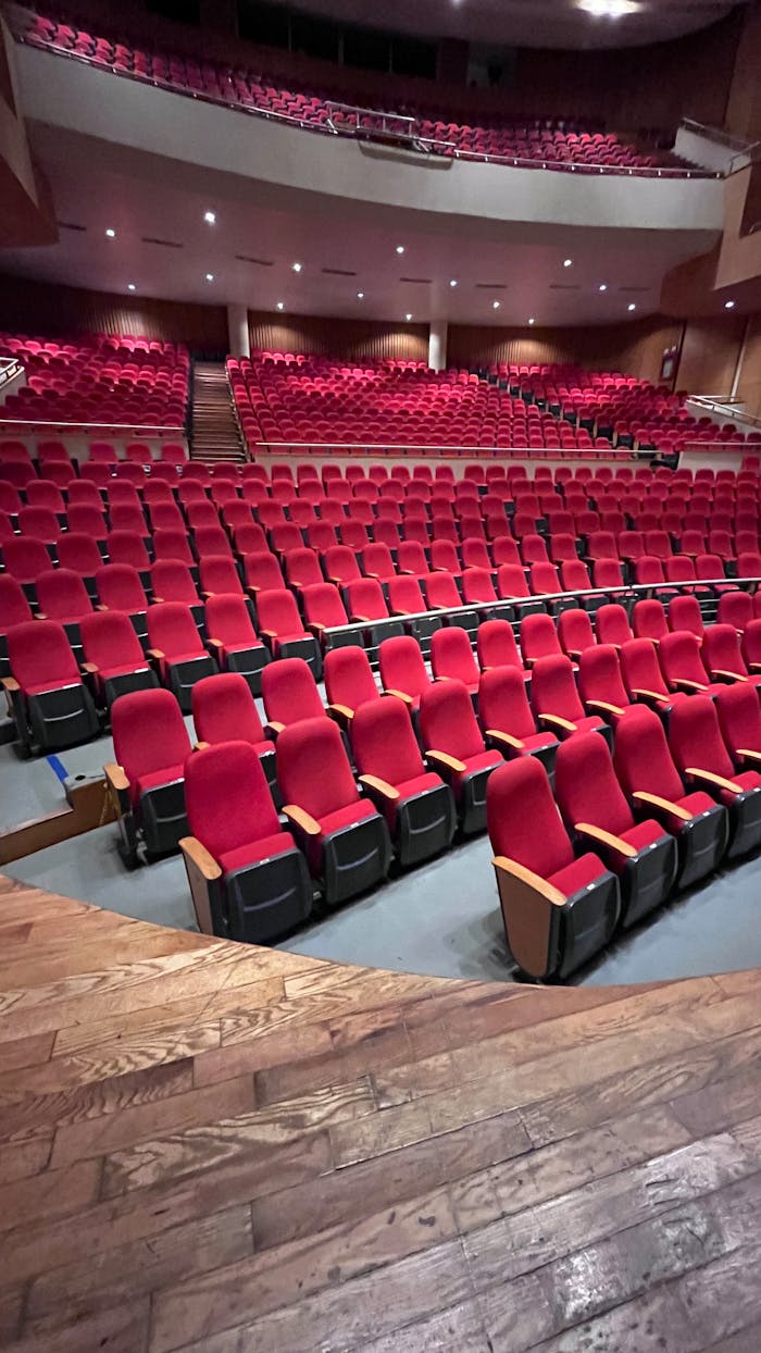 Empty theater with red seats and balcony, perfect for events and performances.