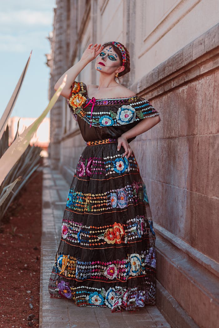 Colorful traditional Mexican dress with vibrant makeup in an outdoor setting, perfect for cultural themes.
